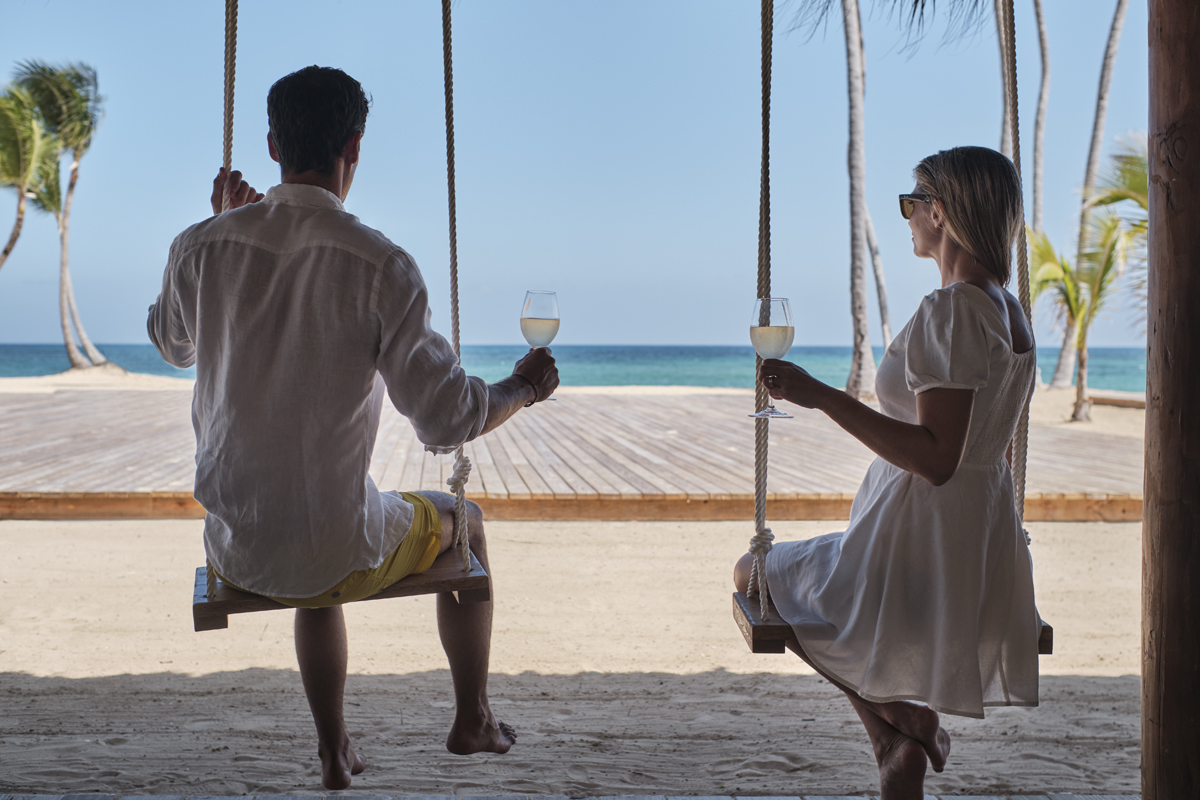 Man and woman sitting on swings by the beach