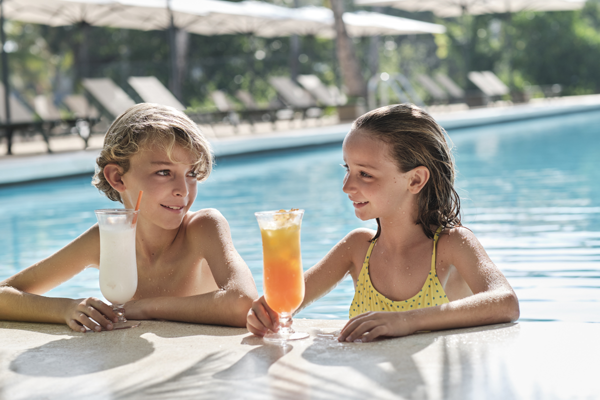 Kids taking a break at the edge of the pool with a poolside cocktail