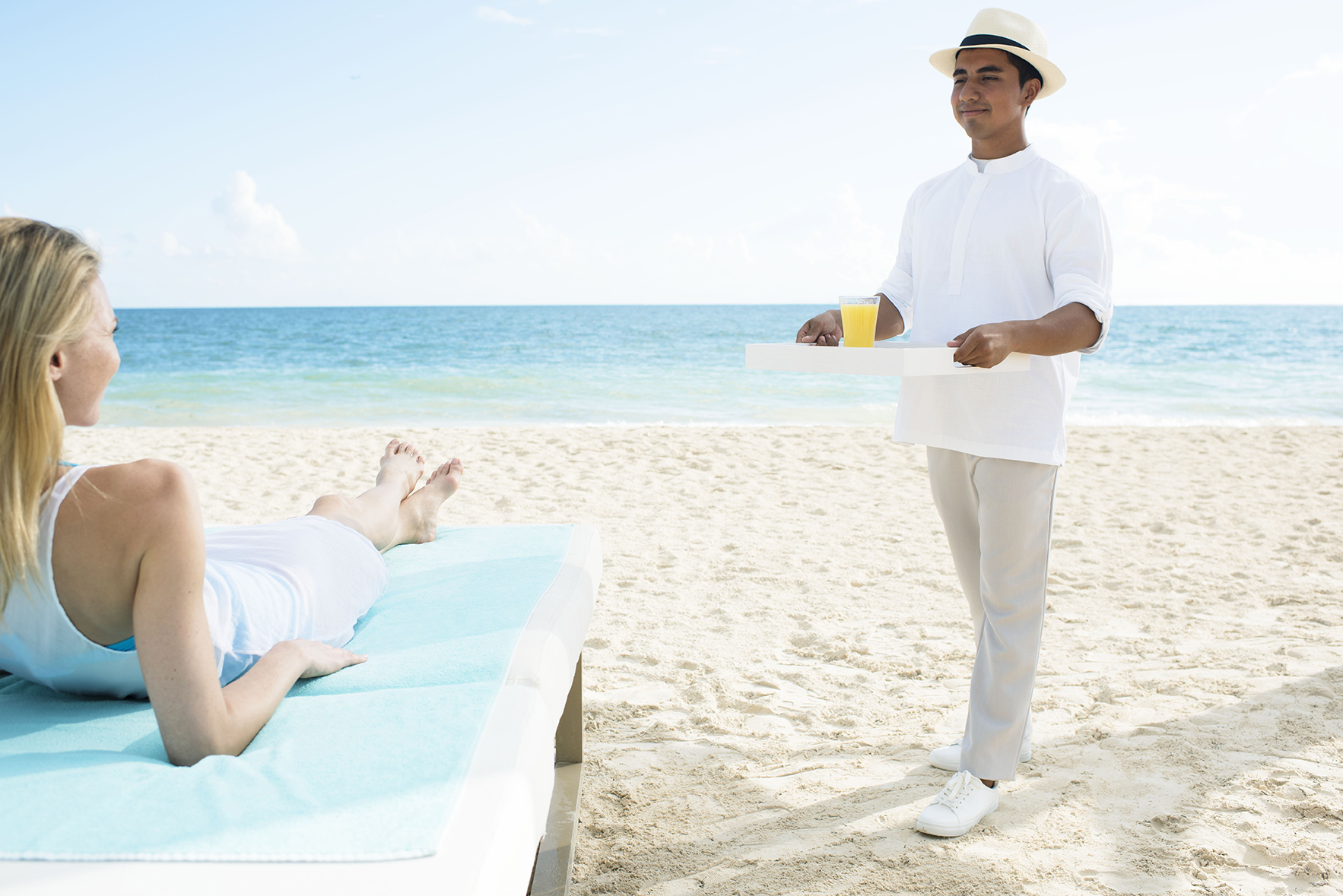 Waiter bringing a cocktail to a lady on the beach